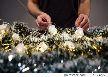 Decorative festive scene, Intimate shot of illuminated cottages with festive accents, Careful arrangement of tiny fairy lights over pine garland and glowing cottages Decorative festive scene, Intimate shot of illuminated cottages with festive accents, Careful arrangement of tiny fairy lights over pine garland and glowing cottages 134653207