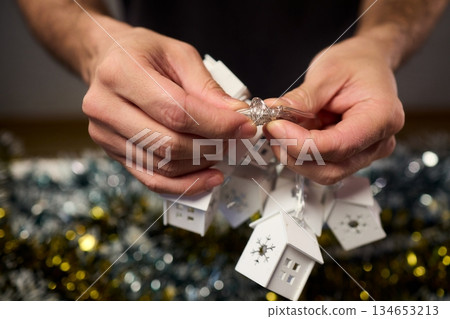 Decorative festive scene, Intimate shot of illuminated cottages with festive accents, Careful arrangement of tiny fairy lights over pine garland and glowing cottages 134653213