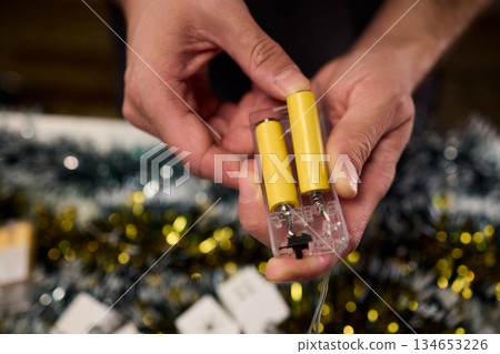 Technician assembling festive light string, Close view of hands installing holiday lighting, Focus on technician connecting string lights during festive preparations Technician assembling festive light string, Close view of hands installing holiday lighting, Focus on technician connecting string lights during festive preparations 134653226