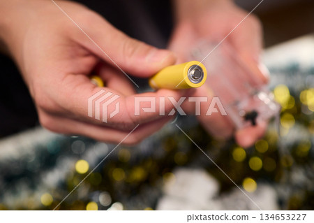 Technician assembling festive light string, Close view of hands installing holiday lighting, Focus on technician connecting string lights during festive preparations Technician assembling festive light string, Close view of hands installing holiday lighting, Focus on technician connecting string lights during festive preparations 134653227