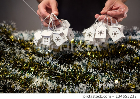 Decorative festive scene, Intimate shot of illuminated cottages with festive accents, Careful arrangement of tiny fairy lights over pine garland and glowing cottages Decorative festive scene, Intimate shot of illuminated cottages with festive accents, Careful arrangement of tiny fairy lights over pine garland and glowing cottages 134653232