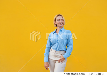 Smiling businesswoman in blue shirt standing 134654036