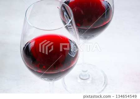 Toasting with red wine - Image of two wine glasses filled with red wine making a toast Toasting with red wine - Image of two wine glasses filled with red wine making a toast 134654549