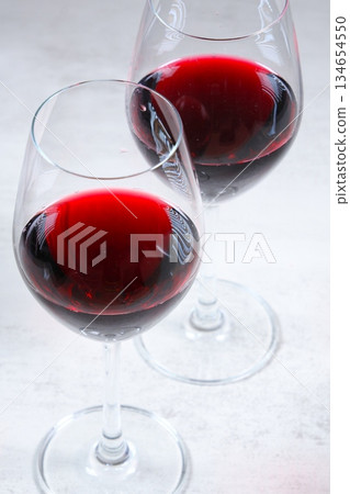 Toasting with red wine - Image of two wine glasses filled with red wine making a toast Toasting with red wine - Image of two wine glasses filled with red wine making a toast 134654550
