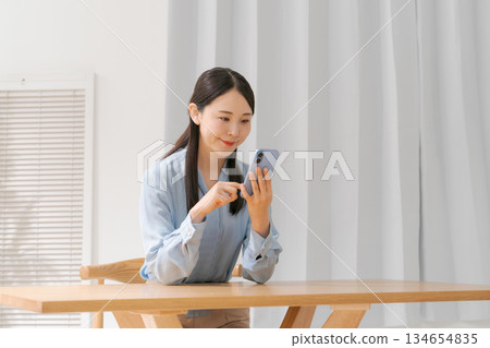 一個操作智能手機的年輕女子 一個操作智能手機的年輕女子 134654835
