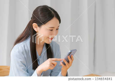 A young woman operating a smartphone A young woman operating a smartphone 134654841