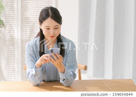 一個操作智能手機的年輕女子 一個操作智能手機的年輕女子 134654844