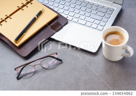 一張圖片：在辦公桌前拿著筆記型電腦和筆記型電腦工作，同時喝著現煮的美味咖啡。 134654862