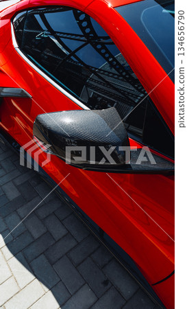 Bright red sports car parked with sleek carbon fiber side mirror on a sunny day 134656790