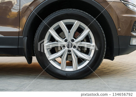 Modern car wheel design on a sleek vehicle parked on a paved street Modern car wheel design on a sleek vehicle parked on a paved street 134656792