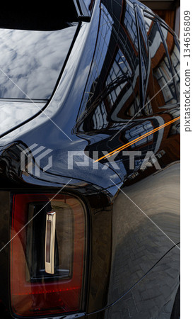 Elegant black car reflects architecture of urban environment on a sunny day Elegant black car reflects architecture of urban environment on a sunny day 134656809