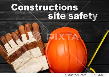 Constructions site safety gear includes hard hat and gloves on wooden background 134656813