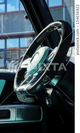 Close-up view of a modern steering wheel in a luxury vehicle showcasing sleek design and technology Close-up view of a modern steering wheel in a luxury vehicle showcasing sleek design and technology 134656922