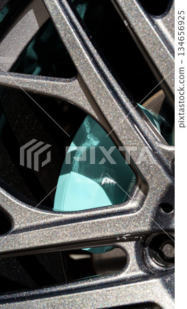 Close-up of a shiny teal brake caliper through a stylish alloy wheel Close-up of a shiny teal brake caliper through a stylish alloy wheel 134656925