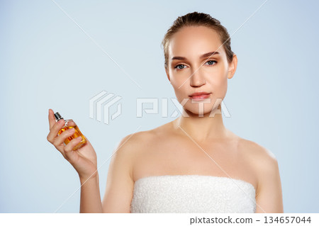 Woman holds a small bottle of yellow liquid in a light background 134657044