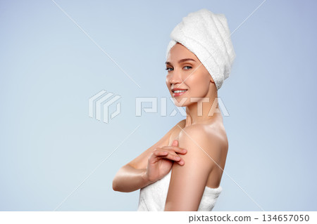 Woman in towel poses for a beauty image with a relaxed smile 134657050