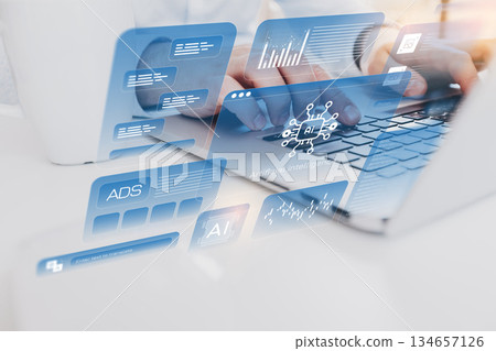 Using technology for digital tasks in an office setting with laptops and data displays 134657126