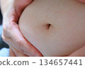胖女人雙手摀著肚子，腹部肥胖體型 134657441