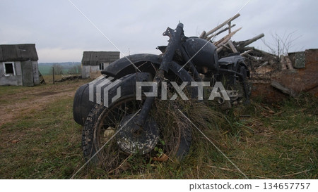 charred motorcycle debris scattered across rural landscape emphasizing violence, burned motorcycle wreckage with warped frame and scorched rubber highlighting past violence in rural setting charred motorcycle debris scattered across rural landscape emphasizing violence, burned motorcycle wreckage with warped frame and scorched rubber highlighting past violence in rural setting 134657757
