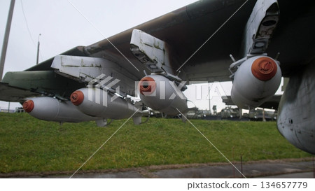 three rocket pods mounted under wing with orange safety caps, damp grass and apron background, close framing on pylons and connectors, atmospheric overcast light suggesting early morning strike three rocket pods mounted under wing with orange safety caps, damp grass and apron background, close framing on pylons and connectors, atmospheric overcast light suggesting early morning strike 134657779