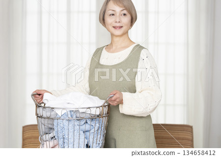 Senior woman doing housework laundry Senior woman doing housework laundry 134658412