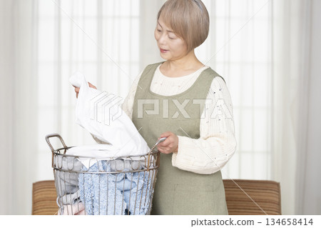 Senior woman doing housework laundry Senior woman doing housework laundry 134658414