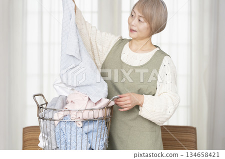 Senior woman doing housework laundry Senior woman doing housework laundry 134658421