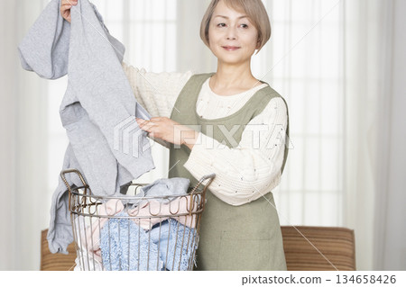 Senior woman doing housework laundry Senior woman doing housework laundry 134658426
