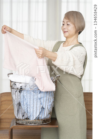 Senior woman doing housework laundry Senior woman doing housework laundry 134658429