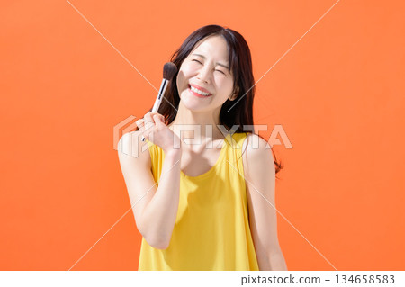 Woman holding a makeup brush Woman holding a makeup brush 134658583