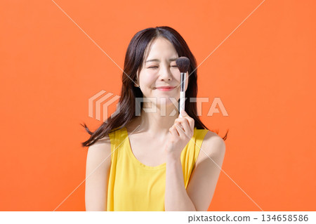 Woman holding a makeup brush Woman holding a makeup brush 134658586