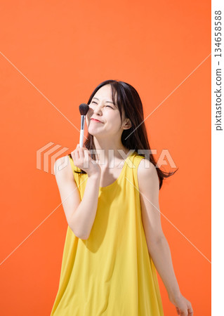 Woman holding a makeup brush Woman holding a makeup brush 134658588