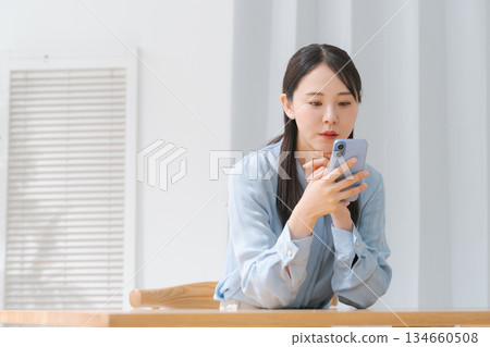A young woman operating a smartphone 134660508