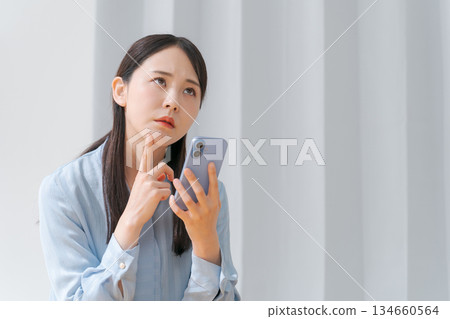 A worried young woman looking at a smartphone 134660564