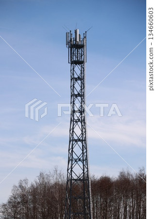 Tall tower with a lot of antennas on top 134660603