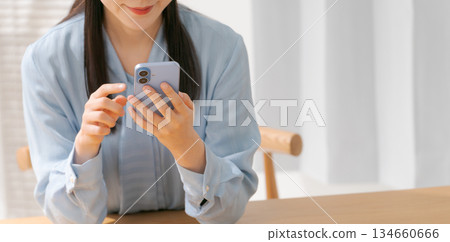 A young woman operating a smartphone (banner) 134660666