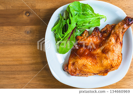Roast chicken served on a white plate on a wooden table 134660969