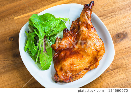 Roast chicken served on a white plate on a wooden table 134660970
