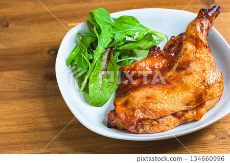 Roast chicken served on a white plate on a wooden table 134660996