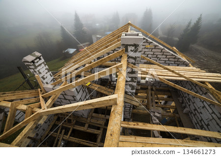 Top view of roof frame from wooden lumber beams and planks on walls made of hollow foam insulation blocks. Building, roofing, construction and renovation concept. 134661273