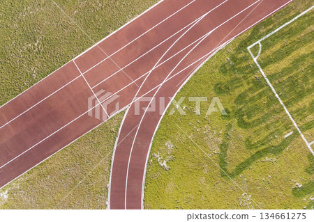 Top view of red running tracks and green grass lawn. Infrastructure for sports activities. Top view of red running tracks and green grass lawn. Infrastructure for sports activities. 134661275