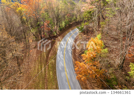 Scenic drive through Tennessee Appalachians at sunset in fall season. Car traveling on curvy forest road under vibrant autumn foliage Scenic drive through Tennessee Appalachians at sunset in fall season. Car traveling on curvy forest road under vibrant autumn foliage 134661361
