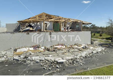 Ruined building in need of repair. Wind damaged house roof with missing asphalt shingles and collapsed wall after hurricane Ian in Florida Ruined building in need of repair. Wind damaged house roof with missing asphalt shingles and collapsed wall after hurricane Ian in Florida 134661377
