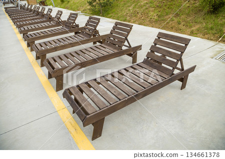 Row of empty wooden beach chairs near water outdoors. Row of empty wooden beach chairs near water outdoors. 134661378