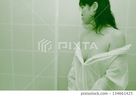 一名成年女性正在脫掉一件白襯衫 一名成年女性正在脫掉一件白襯衫 134661425