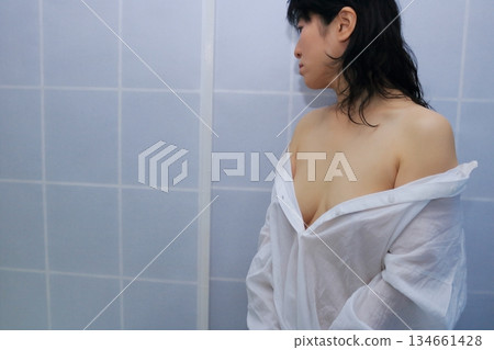 一名成年女性正在脫掉一件白襯衫 一名成年女性正在脫掉一件白襯衫 134661428