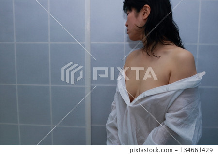 一名成年女性正在脫掉一件白襯衫 一名成年女性正在脫掉一件白襯衫 134661429