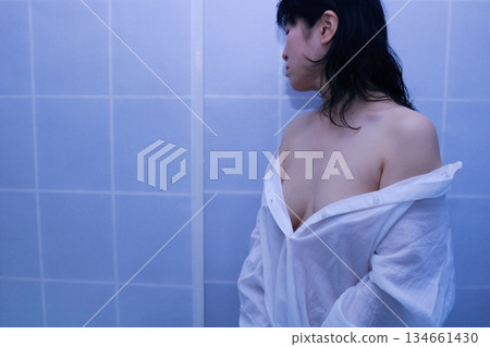 一名成年女性正在脫掉一件白襯衫 一名成年女性正在脫掉一件白襯衫 134661430