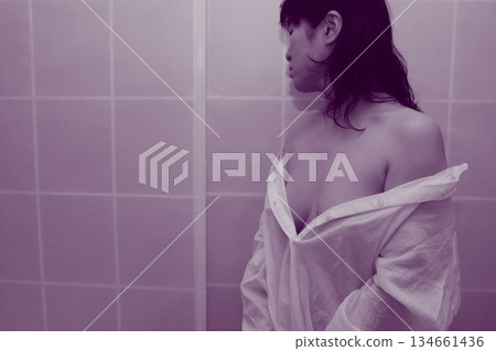 An adult woman taking off a white shirt 134661436