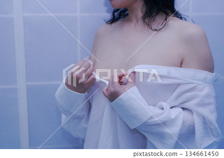 一名成年女性正在脫掉一件白襯衫 134661450